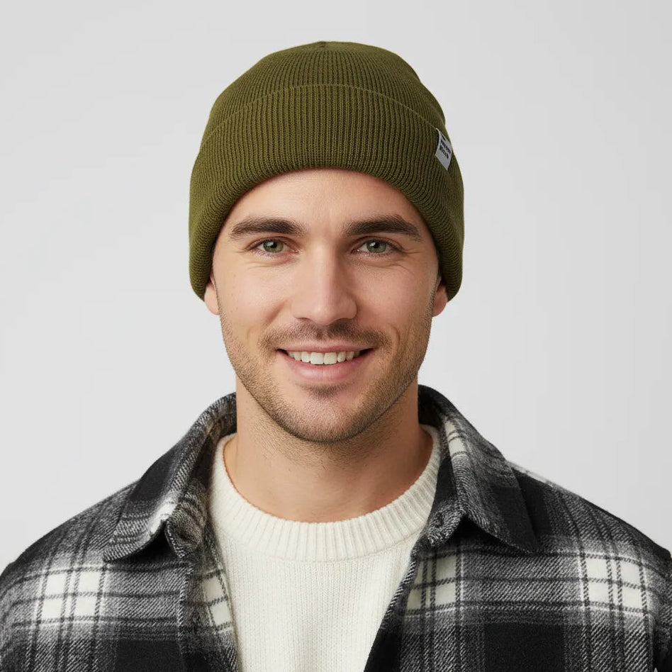 Man wearing a green beanie and plaid jacket on a plain background