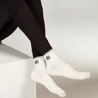 White socks with black snowflake designs worn by a person against a neutral background